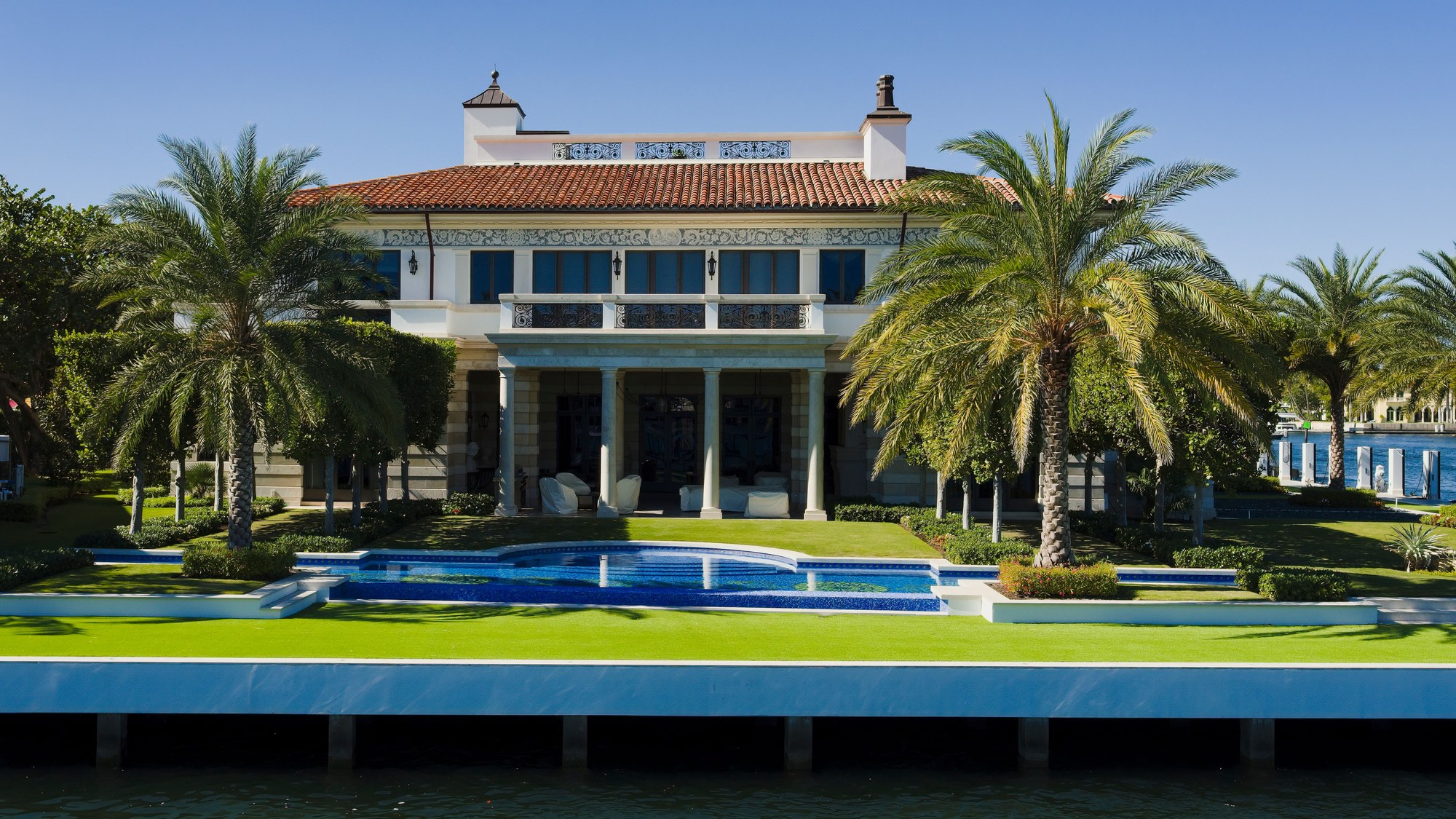 Grand waterfront villa with a swimming pool, formal lawn and mature palms